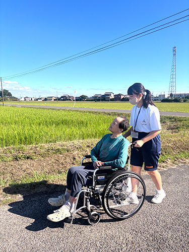 高齢者が乗る車いすを押す中学生